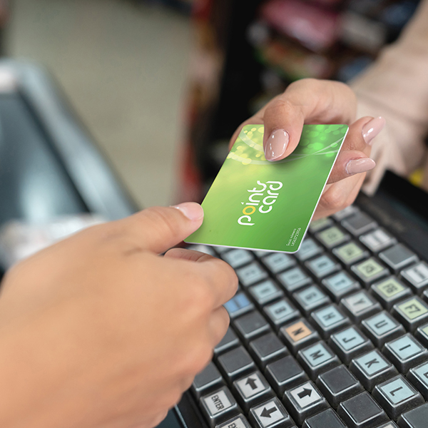 A close-up of a person handing a points card to a cashier.