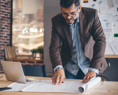 A man consults blueprints at a conference table.