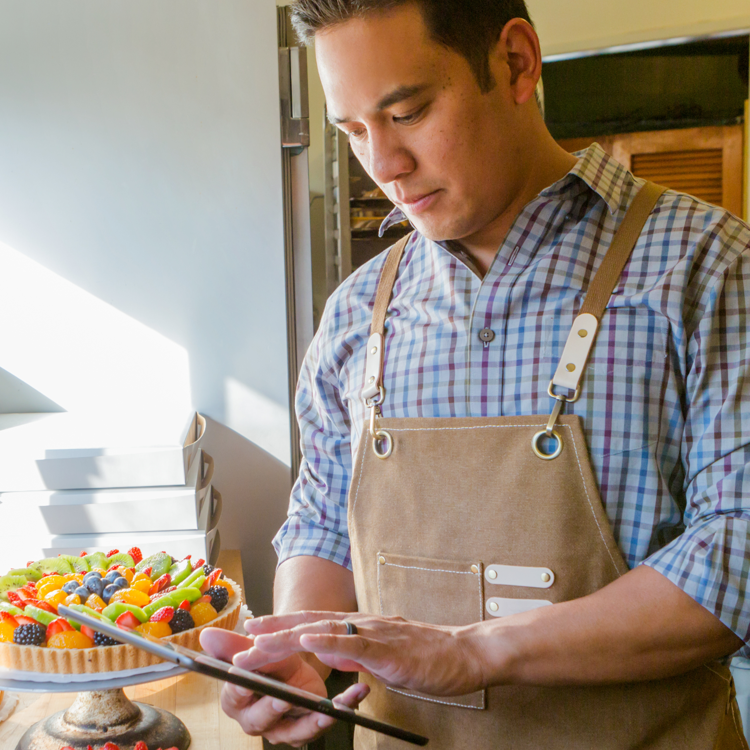 A pastry chef checks his smart tablet.