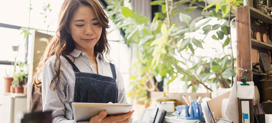 A small business owner smiles as she consults her smart tablet.