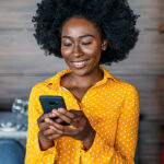 A woman smiles as she looks at her mobile phone