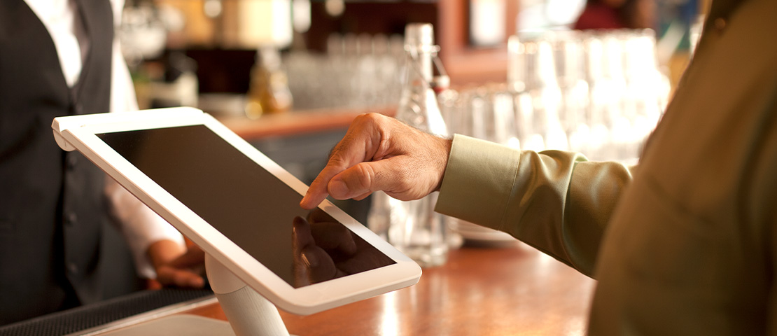 A person taps on a tablet in a restaurant.