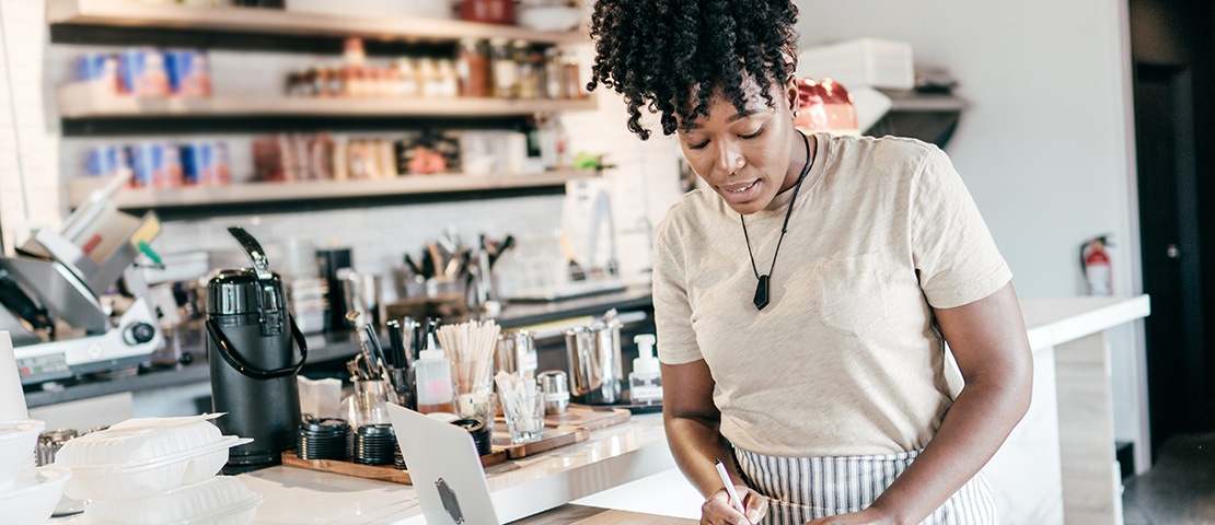 A business owner takes notes at her laptop.