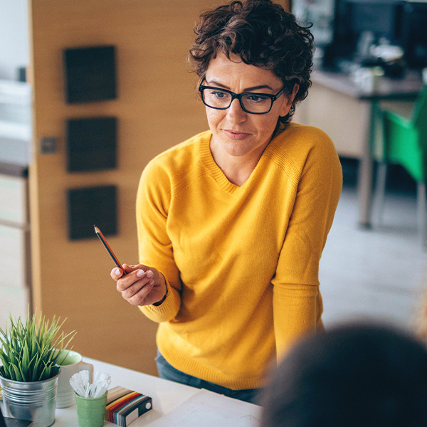 A woman leads a discussion with coworkers around an office table.