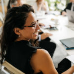 A woman smiles in a meeting while sitting at conference table